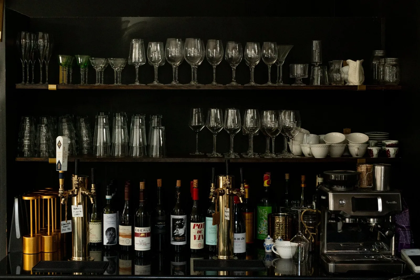 Glassware and bottles ranked along the dark shelves behind the bar