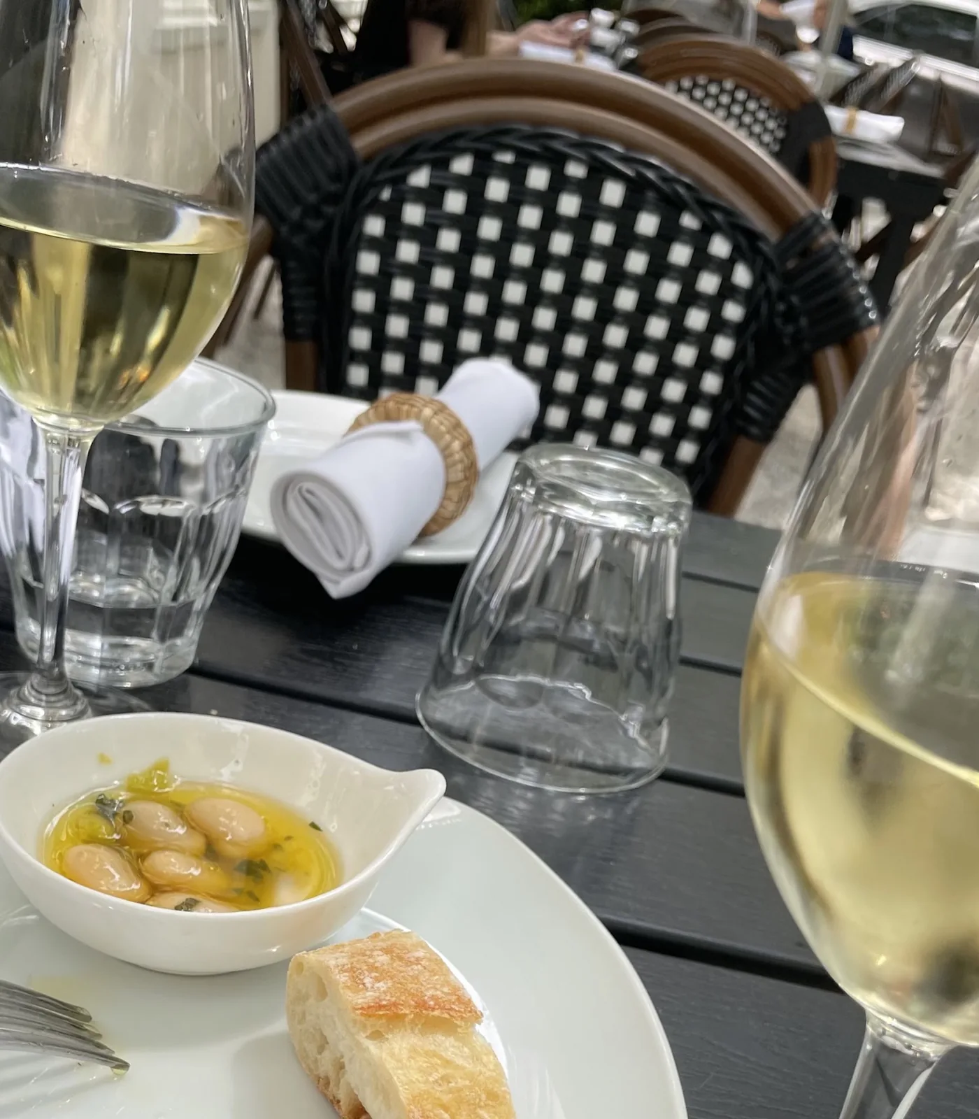Chilled white wine, marinated butter beans and bread on a patio table at Bistro Ten