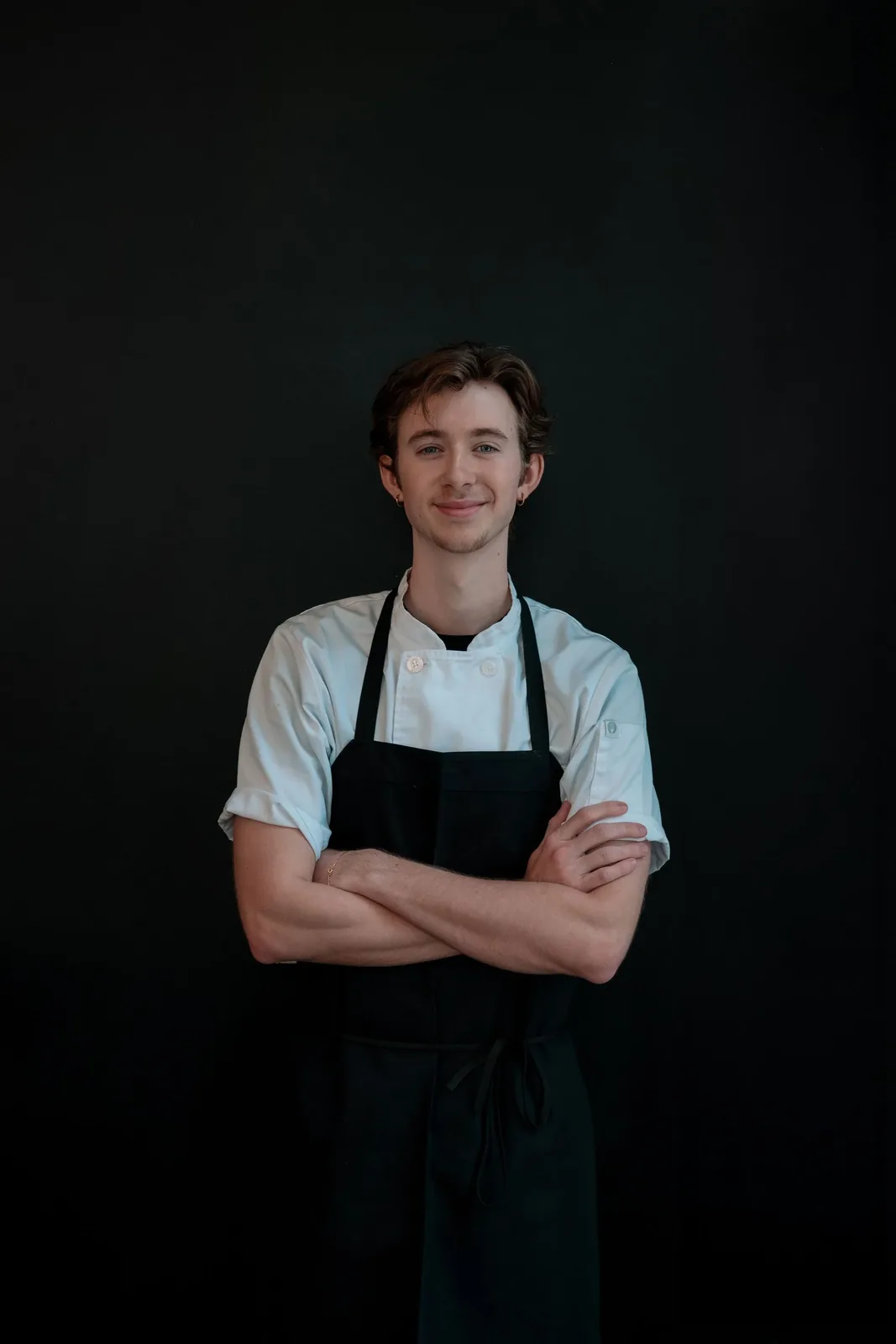 Christian Ramsey, sous chef at Bistro Ten, in an apron against a dark backdrop