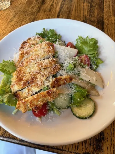 A crisp parmesan-crusted chicken cutlet over salad