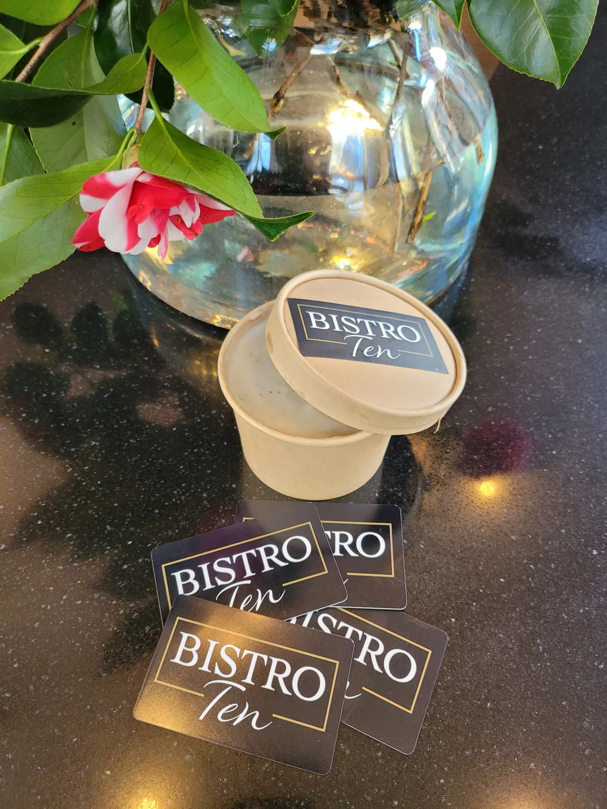 Bistro Ten coasters on a table beside a camellia in a glass vase