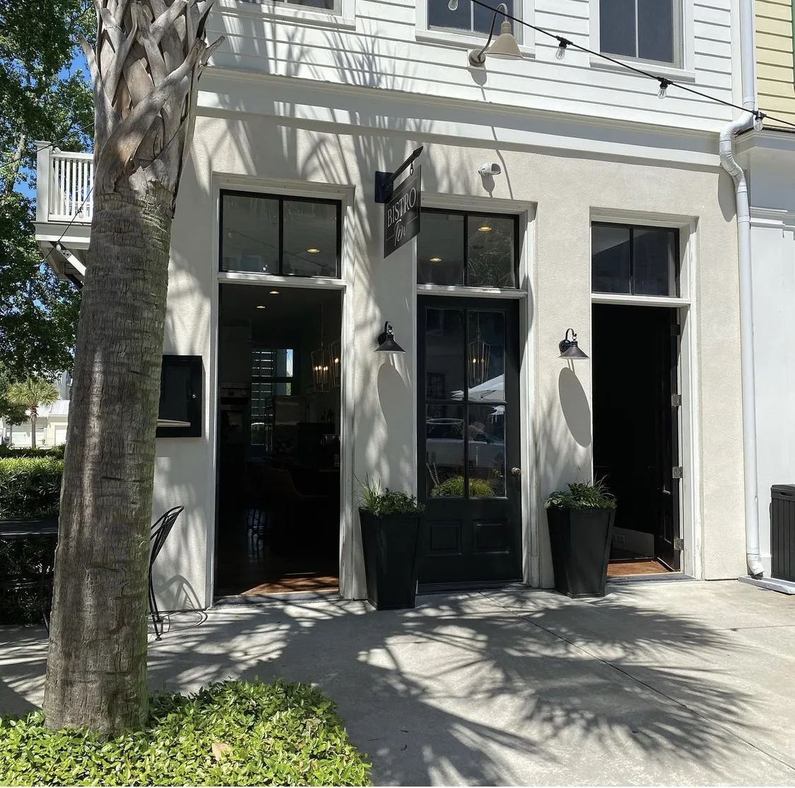 The white storefront of Bistro Ten under live oaks in Habersham Marketplace