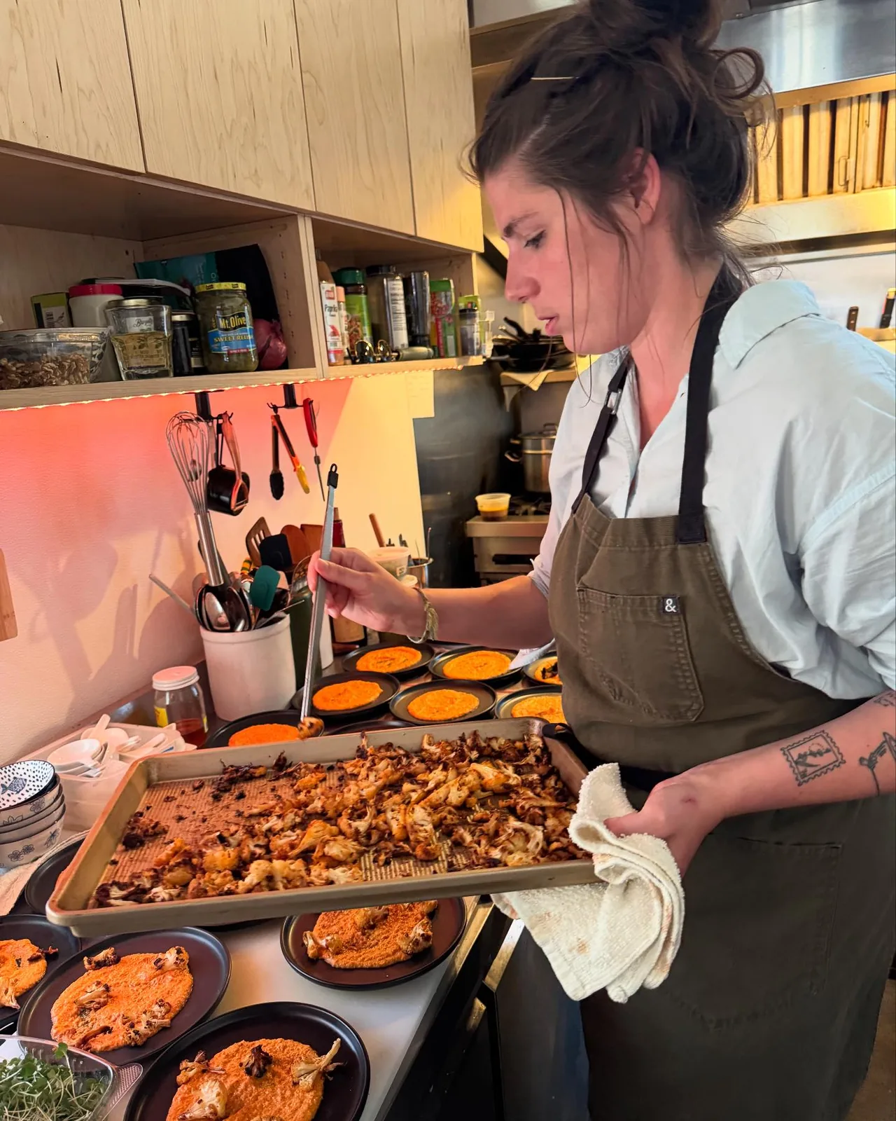 A cook plating in the Bistro Ten kitchen beside trays of prepared food