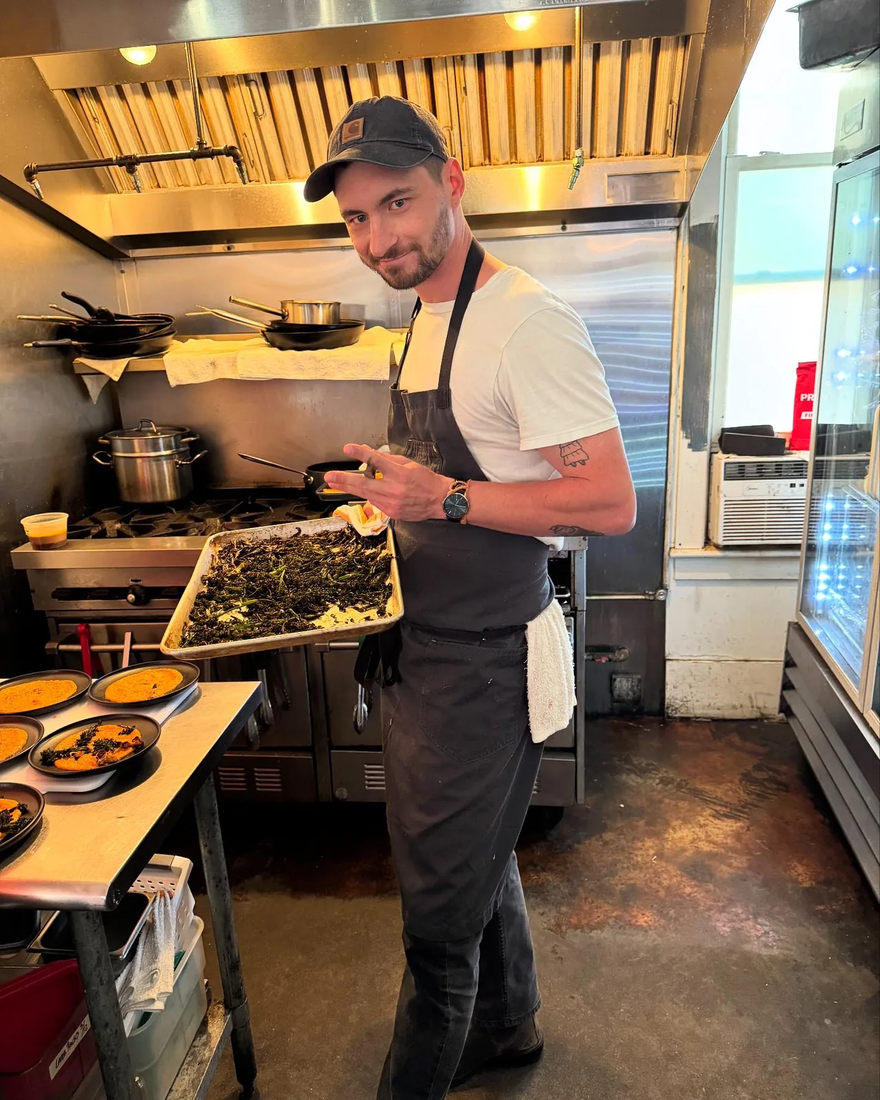 A chef carrying trays of prepared food through the Bistro Ten kitchen
