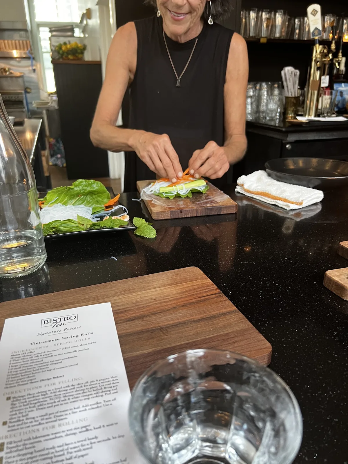 A cook rolling fresh spring rolls at the bar during a Bistro Ten cooking class
