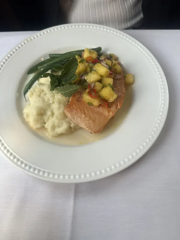 Salmon served over grits with green beans and pineapple salsa