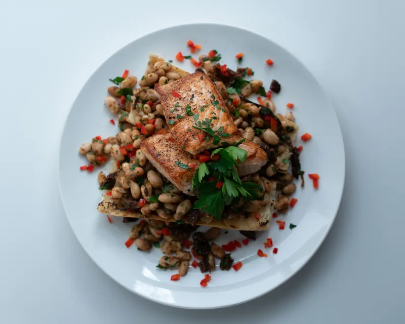 A seared salmon fillet plated over beans and greens